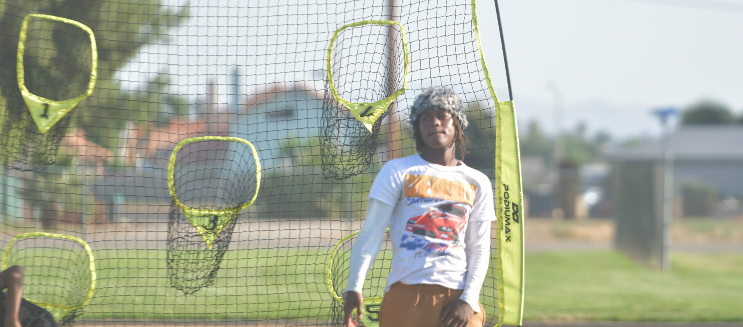 Teenager standing in front of sports training nets during a community development session, representing the Power of Water Foundation’s goal to build resilience and long-term impact.