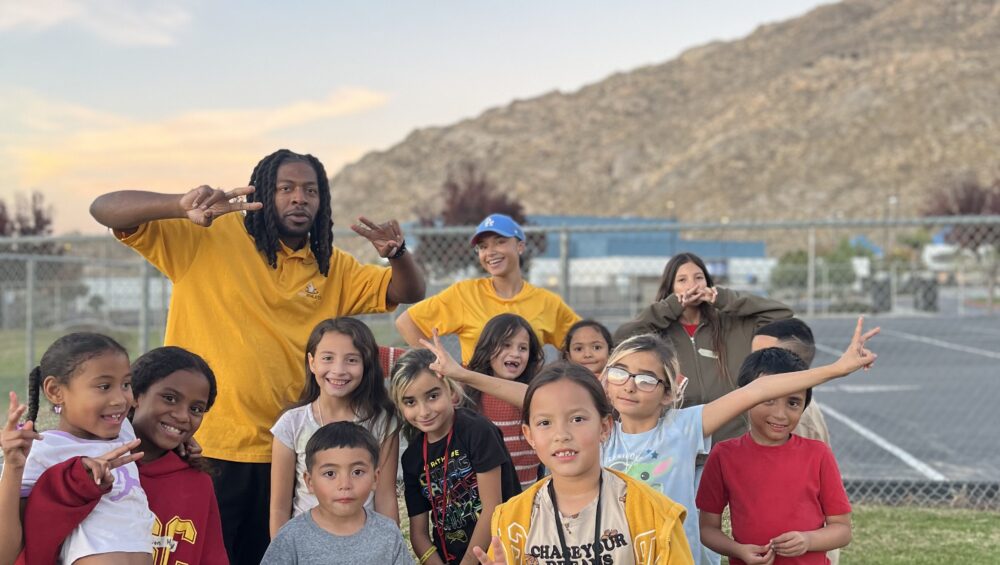 A mentor posing with a diverse group of smiling children during a Power of Water Foundation mentorship session, promoting leadership, confidence, and emotional growth.